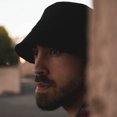 Closeup shot of a caucasian boy with a septum piercing in a black hat - obrazy, fototapety, plakaty