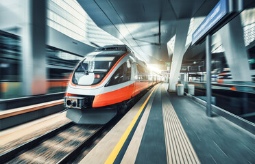 High speed train in motion inside modern train station in Vienna. Fast red intercity passenger train with motion blur effect. Railway platform. Railroad in Europe. Commercial transportation. Transport - obrazy, fototapety, plakaty