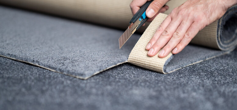 Handyman cutting a new carpet with a carpet cutter..