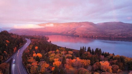 Aerial view of a lake surrounded by trees and hills near a highway in the Dalles, Oregon at sunset