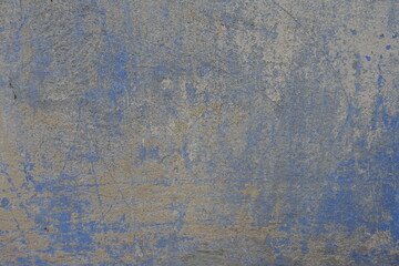Uneven surface of blue and yellow old, faded and scratched painted wall