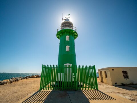 Low angle shot of green South Mole lighthouse under blue bright sky