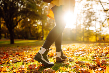 Women's feet walk on autumn leaves in the forest. Rest, relaxation, lifestyle concept.