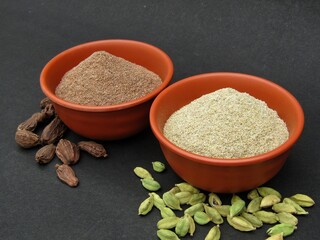 Black cardamom powder and green cardamom powder in bowls 