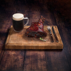 Smoked pork knuckle eisbein and dark beer. German festival food concept. Dark wood background