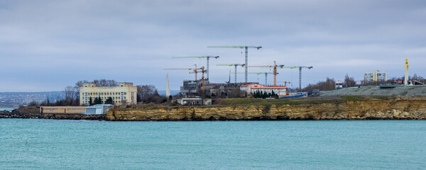 Fototapeta premium Construction on the sea coast. Lots of construction cranes. Improvement and development in the Crimea. City of Sevastopol.