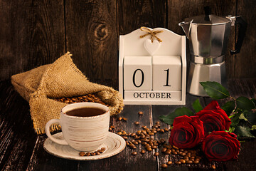 The first of October is the international coffee day in the calendar. Composition with a white cup of coffee, coffee beans in a bag, a geyser coffee maker and red roses on a dark wooden background.