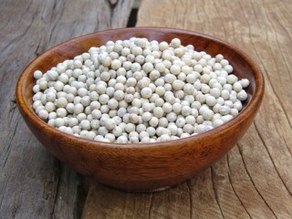 White pepper in a bowl on wooden background 