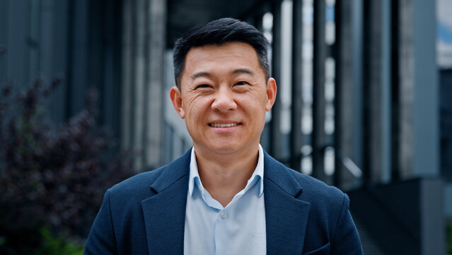 Close up front view in city outdoors Asian Korean man business boss leader company CEO smiling glad happy middle-aged businessman professional financial advisor executive leader manager male lawyer