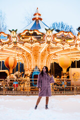 A girl in a fur coat near a beautiful French merry-go-round Snow winter