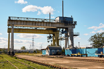 Industrial crane with containers and railway in background