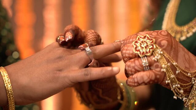 Indian bride groom wears the ring on his finger and vows and then the bride wears a ring on a finger to her husband and vows and the priest shakes hands