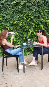 Two friends recording themselves with an old video camera while having coffee