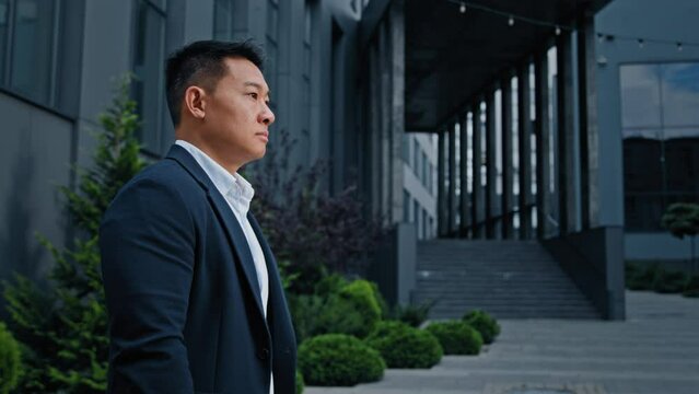 Stylish Asian middle-aged businessman employer entrepreneur man in business suit walk going to city near skyscraper of office company building rush hurry to work walking to job interview investment