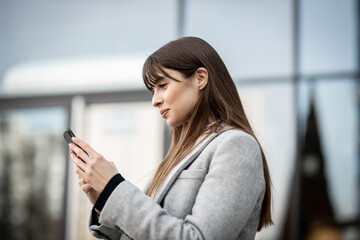 Fototapeta premium Young and beautiful business woman using mobile and laughing outdoors