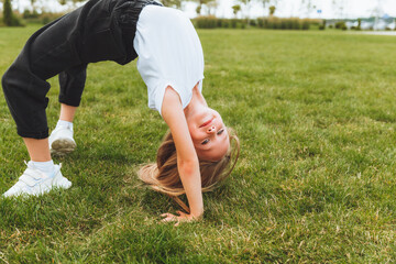 A little girl does gymnastics on the grass. a child does gymnastics in the fresh air in the park.