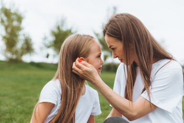 A happy mother and her daughter are sitting on the grass in the park and hugging. mother and daughter. family.joyful mom and little girl