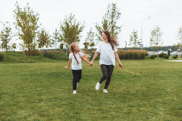 Mother and daughter play and run around the park on a beautiful day. the family is having fun in the park on the grass. morning jog.