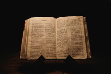 Closeup shot of a historic old Bible open on the Amos pages on display in a dark room