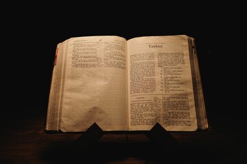 Closeup shot of a historic old Bible open on the Ezekiel pages on display in a dark room
