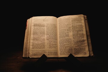 Closeup shot of a historic old Bible open on the Daniel pages on display in a dark room