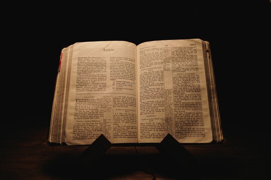 Closeup shot of a historic old Bible open on the Amos pages on display in a dark room