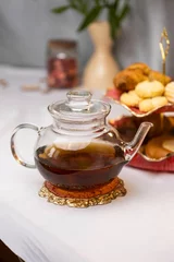 Zelfklevend Fotobehang Vertical shot of glass teapot with different desserts on a table in a kitchen © Vladislav šmigelski/Wirestock Creators