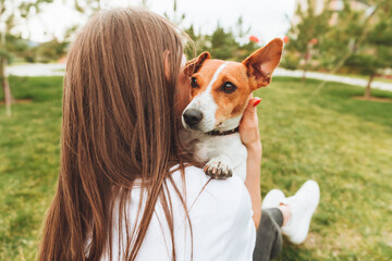 A woman holds and hugs her Jack Russell Terrier dog in the park. Loyal best friends since childhood. a woman feeds her dog from the palm of her hand .animal feed