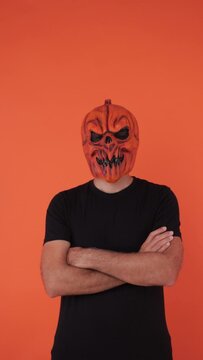 Person with pumpkin mask celebrating Halloween, crossing arms. Celebration concept, All Souls' Day and All Saints' Day.