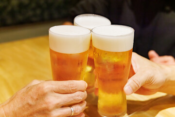 飲食店でジョッキの生ビールを乾杯する人たち