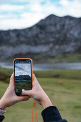 Detalle de chica joven caucásica, haciendo una fotografía con el teléfono móvil a los lagos de Covadonga.