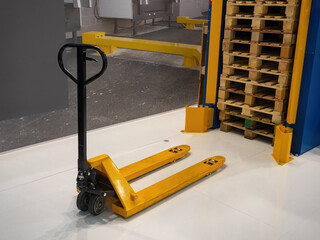 Hand pallet truck. Hydraulic pallet truck on background of warehouse interior. Yellow manual...