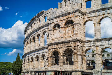 Obraz premium Roman amphitheater in the city of Pula, Croatia. Close-ups on the ancient walls of a Roman building. A beautiful sunny day with fairy-tale clouds in the background