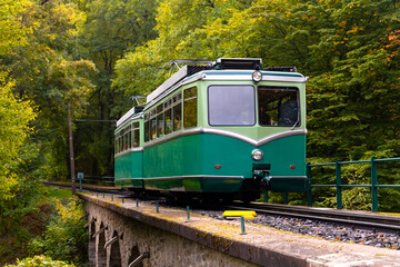 Historic Rack Railway train on a small bridge in Königswinter Germany. Old electric railcar climbing upwards to the “Drachenfels“, a popular tourist attraction near Bonn in romantic Rhine valley.