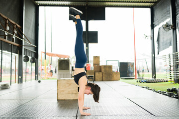 Fototapeta na wymiar Athletic woman exercising and doing a headstand at the gym