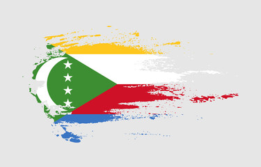 Grunge brush stroke flag of Comoros with painted brush splatter effect on solid background
