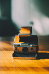 Retro instant camera on a midcentury wooden desk. Polaroid.