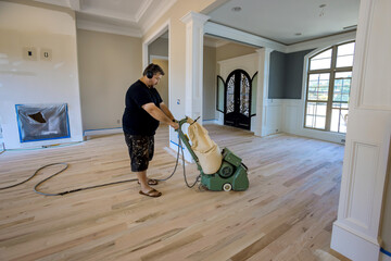 Process grinding a wooden parquet floor in using floor sander of newly constructed house