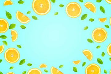 Flat lay of orange slices with green leaves on pastel blue background with gradient light on surface and copy space