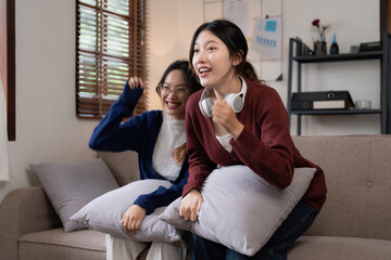Naklejka na ściany i meble Two Young woman cheering together for sport on TV in cozy living room at home
