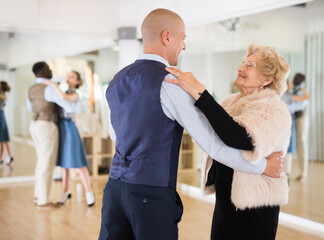 Elderly woman learning ballroom dancing movements in pair - obrazy, fototapety, plakaty