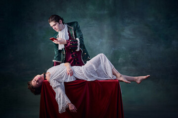 Portrait of man in image of medieval vampire taking selfie of dead woman lying on table over dark...