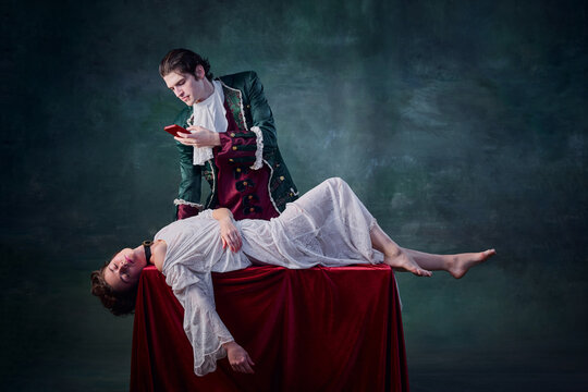 Portrait of man in image of medieval vampire taking selfie of dead woman lying on table over dark green background