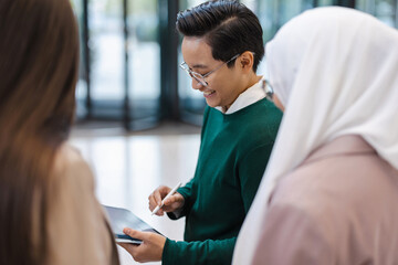 Obraz premium Young businessman showing something to his colleagues on tablet in office 