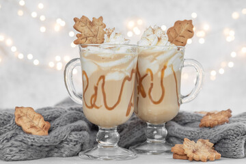 Pumpkin spice latte in a glass mug with caramel and cinnamon cookies with Autumn decoration