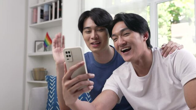 Young Asian gay couple video call to their friends and family with smartphone.