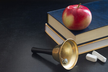 Bell, books and apple on blackboard, back to school concept