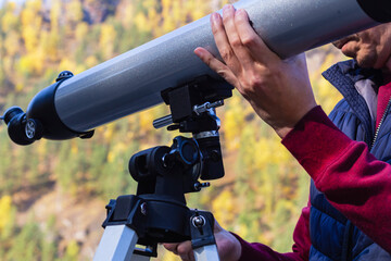 Man's hand holds large gray telescope, attaches stargazing equipment to tripod.