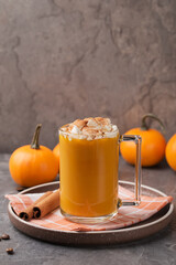 Autumn pumpkin spice latte with cream in mug and mini pumpkins on dark table. Traditional Coffee Drink for Autumn Holidays. Harvest Festival, Happy Thanksgiving. Fall time. Vertical orientation.