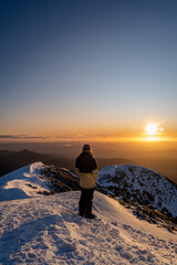 man looking at sunset sky in the mountains